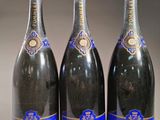 trois bouteilles de champagne posées côte à côte sur une table