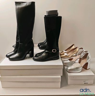 deux paires de bottes à talons hauts noires et blanches posées sur une pile de cartons blancs