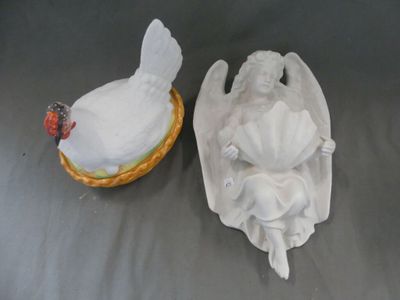 deux figurines d'anges et un poulet posés sur une table