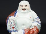 une figurine orientale représentant un Bouddha souriant assis sur un coussin