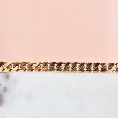 a close up of a gold chain bracelet on a marble surface