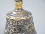 a metal bell with a bird on top of it
