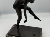 statue en bronze représentant une figure féminine, posée sur un socle en marbre