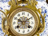 a blue and white vase with a clock on it
