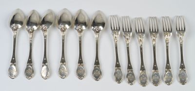 six fourchettes et six cuillères sont alignées sur une surface blanche