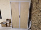 une armoire blanche à porte coulissante, adossée à un mur en briques