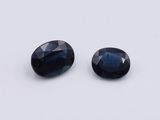 two oval blue sapphires on a white surface