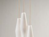 three white vases hanging from a string on a gray wall
