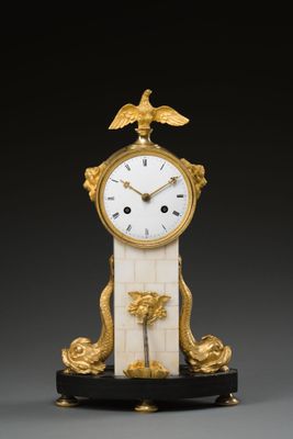 une horloge dorée et blanche surmontée d'un oiseau