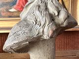 a statue of a bird on a pedestal in front of a painting
