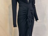 La robe est noire, à manches longues et avec un col en V.