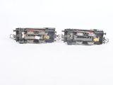 two toy trains sitting side by side on a white surface