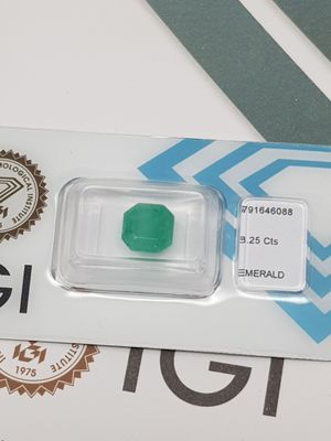 a green emerald in a clear plastic container on a table