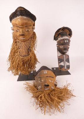 Plusieurs masques africains sont exposés sur un fond blanc.