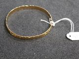 a close up of a gold bracelet with a tag on it