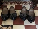 Plusieurs paires de chaussures noires sont alignées sur un sol à carreaux.