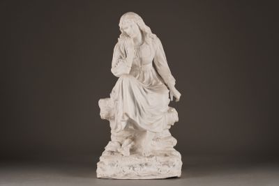 a statue of a woman sitting on a rock with a dog