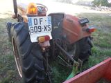 un tracteur garé dans l'herbe, muni d'une plaque d'immatriculation