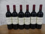 six bouteilles de vin rouge sont alignées sur une table