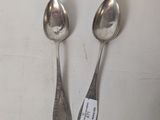 two silver spoons sitting on top of a table next to each other