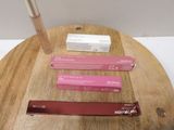 trois gloss posés sur une table en bois, à côté d'une boîte de baume à lèvres