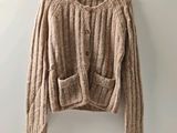 a brown sweater hanging on a hanger against a wall
