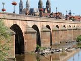 une photo d'un pont enjambant une rivière, avec un bâtiment en arrière-plan
