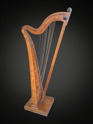 une harpe en bois posée sur un support, sur fond noir