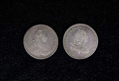 two silver coins sitting on top of a black surface
