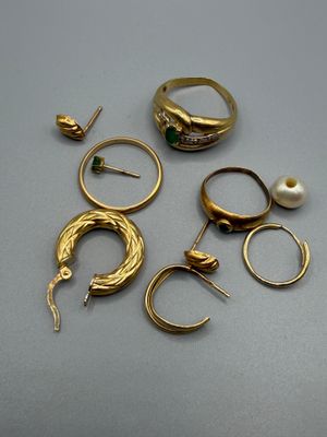 beaucoup de bagues et de boucles d'oreilles en or posées sur une table