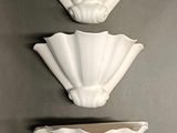 three white wall sconces mounted on a wall in a room