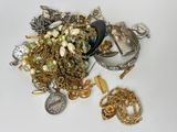 un tas de bijoux en or et en argent posés sur une surface blanche