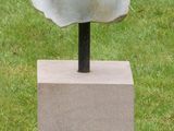 sculpture of a woman ' s head on a pedestal in a grassy area