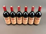six bottles of red wine lined up in a row on a table