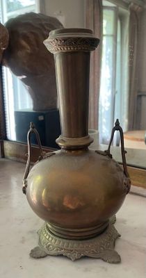 a large brass vase sitting on a table in front of a mirror