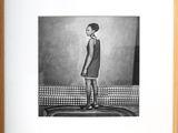 black and white photograph of a young girl standing on a bed