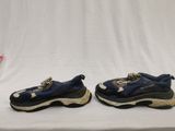 two pairs of blue and black sneakers sitting on a white surface
