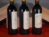 three bottles of red wine sit on a red cloth next to a wooden box