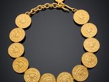 a gold bracelet with a coin design on a black background