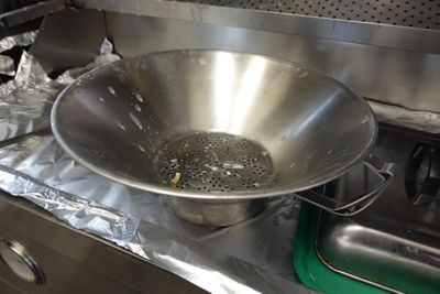 un grand saladier en métal posé sur une cuisinière