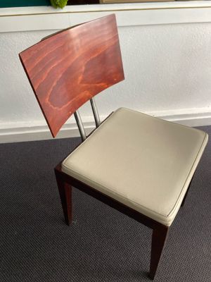a wooden chair with a leather seat in front of a window