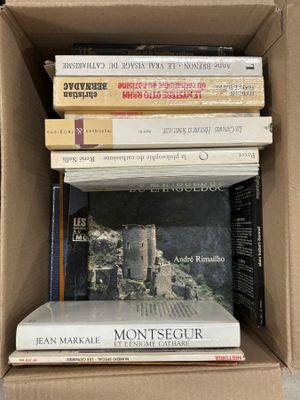 Les livres sont empilés dans une boîte en carton posée sur une table.