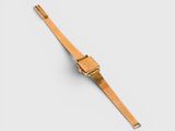 a gold watch on a white surface with a white background