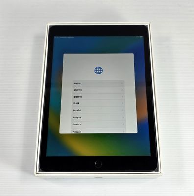 une tablette posée sur une table blanche, à côté d'un clavier