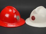 two red and white fire hats sitting next to each other on a black surface