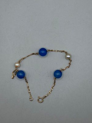 un gros plan d'un bracelet en perles bleues posé sur une surface blanche