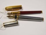 three pens are lined up on top of each other on a white surface