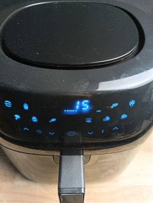 une friteuse à air chaud noire posée sur une table en bois
