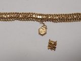 Gros plan sur un bracelet en chaîne en or sur lequel se trouve une pièce de monnaie