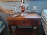 une femme debout à côté d'une table sur laquelle se trouve une lampe